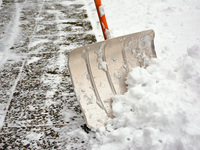 Eine Schneeschaufel räumt den Gehweg