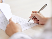 Stift in der Hand mit einem Vertrag