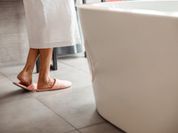 Füße einer älteren Frau neben einer Badewanne