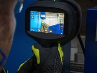 Eine Person verwendet eine tragbare Wärmebildkamera, um eine Maschine in einer industriellen Umgebung zu inspizieren.