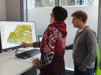 Zwei Mitarbeitende von einem Bildschirm mit CAD-Software