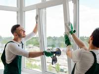 Handwerker bauen ein Fenster ein.