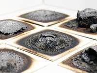 Verschiedene intumeszierende Beschichtungen nach der Beflammung im Laborbrandprüfstand des Fraunhofer WKI. Die Tests geben Aufschluss darüber, mit welcher Rezeptur sich das darunterliegende Holz am besten schützen lässt.