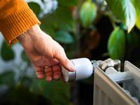 Hand dreht an einem Heizungsthermostat