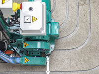 Eine Fräsmaschine bearbeitet einen Estrichboden, um eine Fußbodenheizung zu installieren.