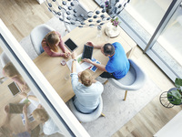 Drei Menschen sitzen an einem Tisch und besprechen etwas.