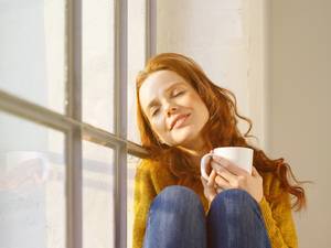 Studie Wohnraumlüftung, Frau sitzt auf Fensterbank
