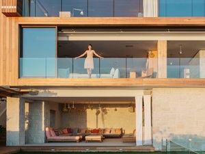 Frau steht in einem offenen Fenster in einem Holzhaus