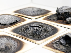 Verschiedene intumeszierende Beschichtungen nach der Beflammung im Laborbrandprüfstand des Fraunhofer WKI. Die Tests geben Aufschluss darüber, mit welcher Rezeptur sich das darunterliegende Holz am besten schützen lässt.