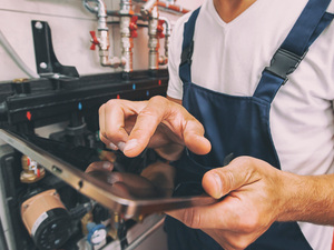 Handwerker mit Tablet im Heizungskeller